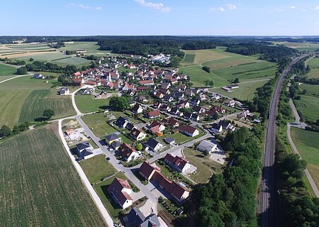 Blick über Weilheim Luftaufnahme des Dorfes Weilheim, mit vielen Häusern, umgeben von Feldern und Wäldern, neben einer Bahnstrecke.