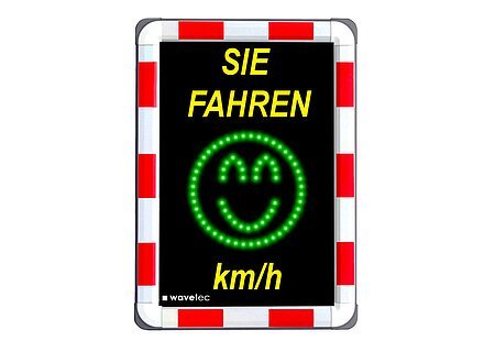 Geschwindigkeitsmessungen Bild eines Geschwindigkeitsmessgeräts im Straßenverkehr, darauf oben gelber Text "Sie fahren" und unten "km/h". Dazwischen ein grünes Smiley-Gesicht aus LEDs. Der Rand außen ist rot/weiß.