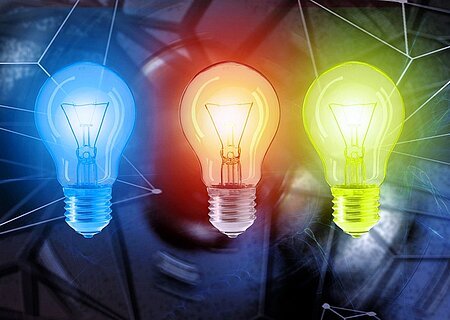 Energie-Versorgung Drei Glühbirnen nebeneinander in Blau, Rot und Gelb leuchten vor einem dunkelblauen Hintergrund mit Linien.
