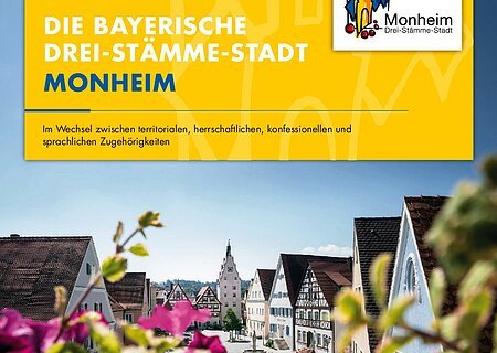 Drei-Stämme-Stadt Vorstellung der bayerische "Drei-Stämme-Stadt" Monheim anhand eines Plakats. Auf dem Foto die Stadtansicht von Monheim mit Fachwerkhäusern, blauem Himmel und unscharfen blühenden pinken Blumen im Vordergrund. Oben auf gelbem Hintergrund der dazugehörige Text: "Die bayerische Drei-Stämme-Stadt Monheim". Rechts oben das Logo der Stadt Monheim.