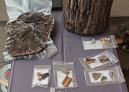 Funde der Ausgrabungen in Monheim im Hof hinter "Das Hotel by Ferber" Verschiedene archäologische Funde eingepackt in Plastiktüten auf einem Tisch ausgelegt, darunter Holzstücke und Proben in kleinen Fläschchen.
