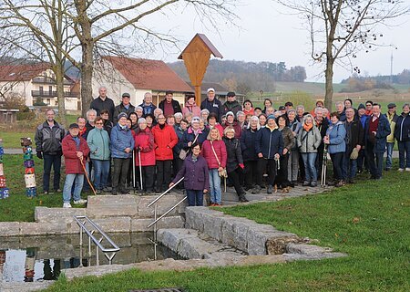 SoMit Wanderung 12.11.2025 in Wolferstadt Große Gruppe älterer Menschen steht im Park vor einem kleinen Wasserbecken mit Treppe und Geländer. Monatliche Wanderung für Senioren vom Verein Soziales Miteinander