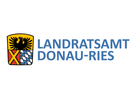 Wappen Landratsamt DONAU-RIES Wappen des Landratsamts DONAU-RIES: auf dem Wappen oben ein schwarzer Adler auf gelbem Hintergrund. darunter links ein gelbes Kreuz auf rotem Hintergrund und rechts davon bayerisches Rautenmuster in weiß-blau. Rechts neben dem Wappen der Text: Landratsamt Donau-Ries.