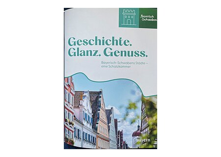 Neue Broschüre "Geschichte.Glanz.Genuss" Titelblatt mit dem Text „Geschichte. Glanz. Genuss. Bayerisch-Schwabens Städte – eine Schatzkammer“ und Bild von historischen Häusern. Neue Broschüre vom Tourismusverband Allgäu-Bayerisch-Schwaben.